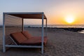 Empty double sun bed on the sandy beach in Dubai, with orange sunset in the background and calm sea Royalty Free Stock Photo