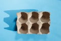 Empty eggs carton box with hard shadows on blue background. Royalty Free Stock Photo