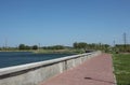 Empty embankment near the lake with a concrete parapet in summer for walking