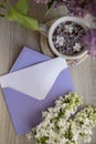 Empty envelope copy space paper note with Tasty black tea in white cup on windowsill with aromatic lilac flowers. Spring