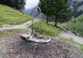 Empty fireplace with black metal grid rust on big gravel place, charred wood between big stones, green fir forest in the Royalty Free Stock Photo