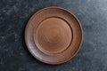 Empty flat plate of red clay over black background . Top view, closeup . Rough ceramic bowl background with copy space Royalty Free Stock Photo