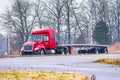 An Empty Flatbed Tractor Trailer Drives in Mixed Winter Weather