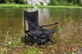 An empty folding chair stands in the water