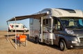 Empty folding chairs and table under canopy near recreational vehicle camper trailer