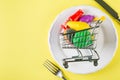 Empty food cart on white plate. Grocery shopping concept, weekly meal planning concept