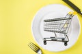 Empty food cart on white plate. Grocery shopping concept, weekly meal planning concept