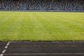 An empty football field. Soccer field grass. Graphite running road track with white marking lines near green football Royalty Free Stock Photo