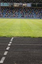 An empty football field. Soccer field grass. Graphite running road track with white marking lines near green football Royalty Free Stock Photo