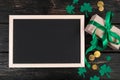 Empty frame for text, gold coins, clover shamrock and gift with green ribbon on a dark wooden background. Good luck Royalty Free Stock Photo