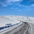 Empty frozen asphalt road and snow covered landscape with mountain over blue sky in winter time Royalty Free Stock Photo