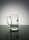 Empty glass beer mug with reflection in glass against grange background