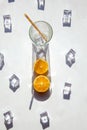 An empty glass with a big shadow around it, ice cubes and orange slices on a white background. Solar photography Royalty Free Stock Photo