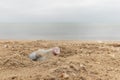 Empty glass bottle on the sand. Garbage on the beach. Sea shore. Environmental pollution. Royalty Free Stock Photo