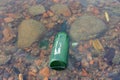 An empty glass bottle thrown into a pond, top view. Pollution of nature.