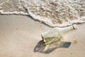 Empty glass bottle washed up as rubbish on a beach, garbage on b Royalty Free Stock Photo