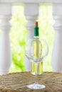 Empty glass bottle with white dry wine on wicker table on garden terrace of villa or mansion. Authentic lifestyle image Royalty Free Stock Photo