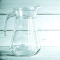 An empty glass carafe for water stands on a white wooden background Royalty Free Stock Photo