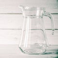 An empty glass carafe for water stands on a white wooden background Royalty Free Stock Photo