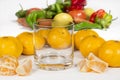 Empty glass cup next to several mandarins and tangerine segments