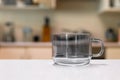 Empty glass cup sitting on laminated kitchen benchtop, Cupboards and cooking appliances in background