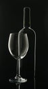Empty glass goblet with black wine bottle on black background Royalty Free Stock Photo
