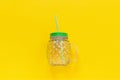 Empty glass jar in form of pineapple with green lid and straw for fruit or vegetable smoothies, cocktails and other beverages on Royalty Free Stock Photo