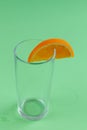 Empty glass with an orange slice isolated on green background Royalty Free Stock Photo