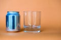 Empty glass sitting next to a can of drink over blurry background Royalty Free Stock Photo