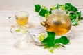 Empty glass teapot and two cups for tea on a wooden table against a background of lime leaves and flowers. Healing tea. Royalty Free Stock Photo