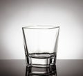 Empty glass of whiskey on black table with reflection on white background