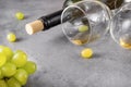 Empty glasses, a bottle, a bunch of green grapes on a gray background close up