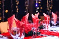 Holiday red decorations in restaurant. Empty glasses set with red holiday decoration and bokeh background.