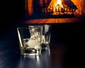 Empty glasses of whiskey with ice cubes in front of the fireplace Royalty Free Stock Photo