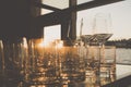 Empty glasses of whiskey and wine at sunset on indoor table with river view windows