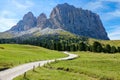 Empty gravel road leads towards the majestic rocky mountain in the Dolomites.