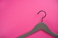Empty gray clothes hanger on bright pink background.