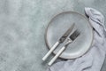 Empty gray plate, knife, fork and napkin on gray grunge background. Table setting. Top view, flat lay. Royalty Free Stock Photo