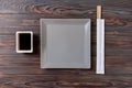 Empty gray square plate with chopsticks for sushi on wooden background. Top view with copy space Royalty Free Stock Photo