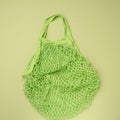 Empty green reusable string bag woven from thread on a green background