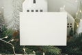 Empty greeting card on background of stylish christmas houses, fir branches with golden lights and tree decorations. Christmas Royalty Free Stock Photo