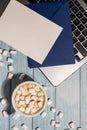 Empty greeting or invitation card mock up blue envelope with white cup of coffee and marshmallows laptop keyboard on Royalty Free Stock Photo