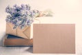 Empty greeting kraft card in front of a lavender bouquet, wrapped gift and old book over a white wood background. Vintage style. Royalty Free Stock Photo
