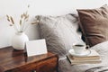 Empty greeting, place card mockup on retro wooden bedside table. Modern white ceramic vase with dry Lagurus ovatus grass