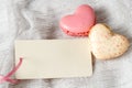 Empty greeting valentines day card or blank label for text and two macaroons in heart shape on light grey textile background Royalty Free Stock Photo