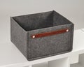 Empty grey felt storage box with leather handle sitting on white shelf Royalty Free Stock Photo