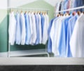 Empty stone surface and clean clothes on hangers in dry-cleaning, space for text Royalty Free Stock Photo