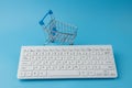 Empty Groceries trolley with keyboard on blue background. Online Shopping, internet shopping Concept Royalty Free Stock Photo