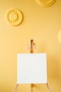 Empty grunge easel in a light room, art background. Yellow bright concrete wall Royalty Free Stock Photo