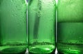 Empty and half-empty green glass bottles. Close-up of drops on glass. Royalty Free Stock Photo